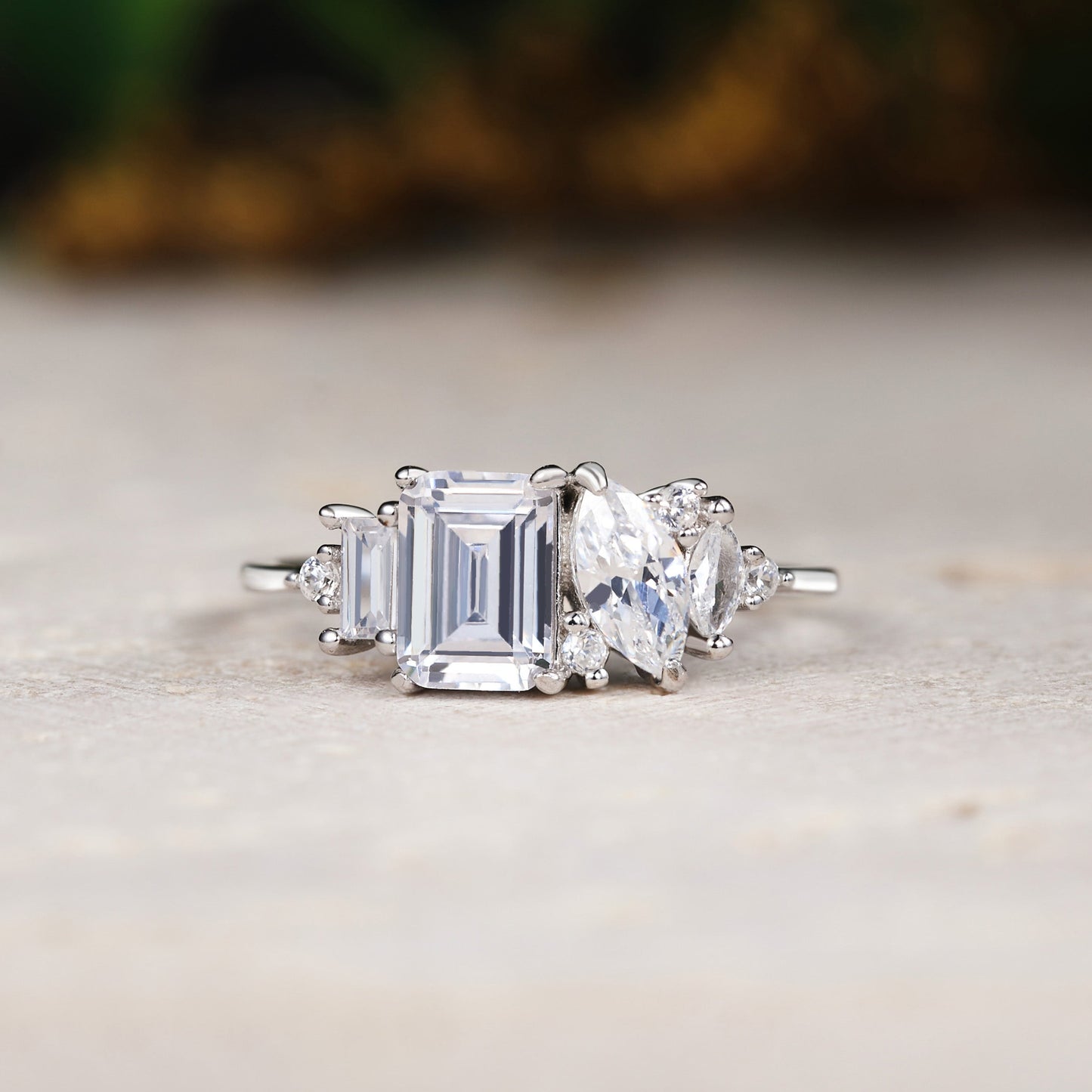 Diamond ring with emerald-cut center stone and baguette side stones on a neutral background