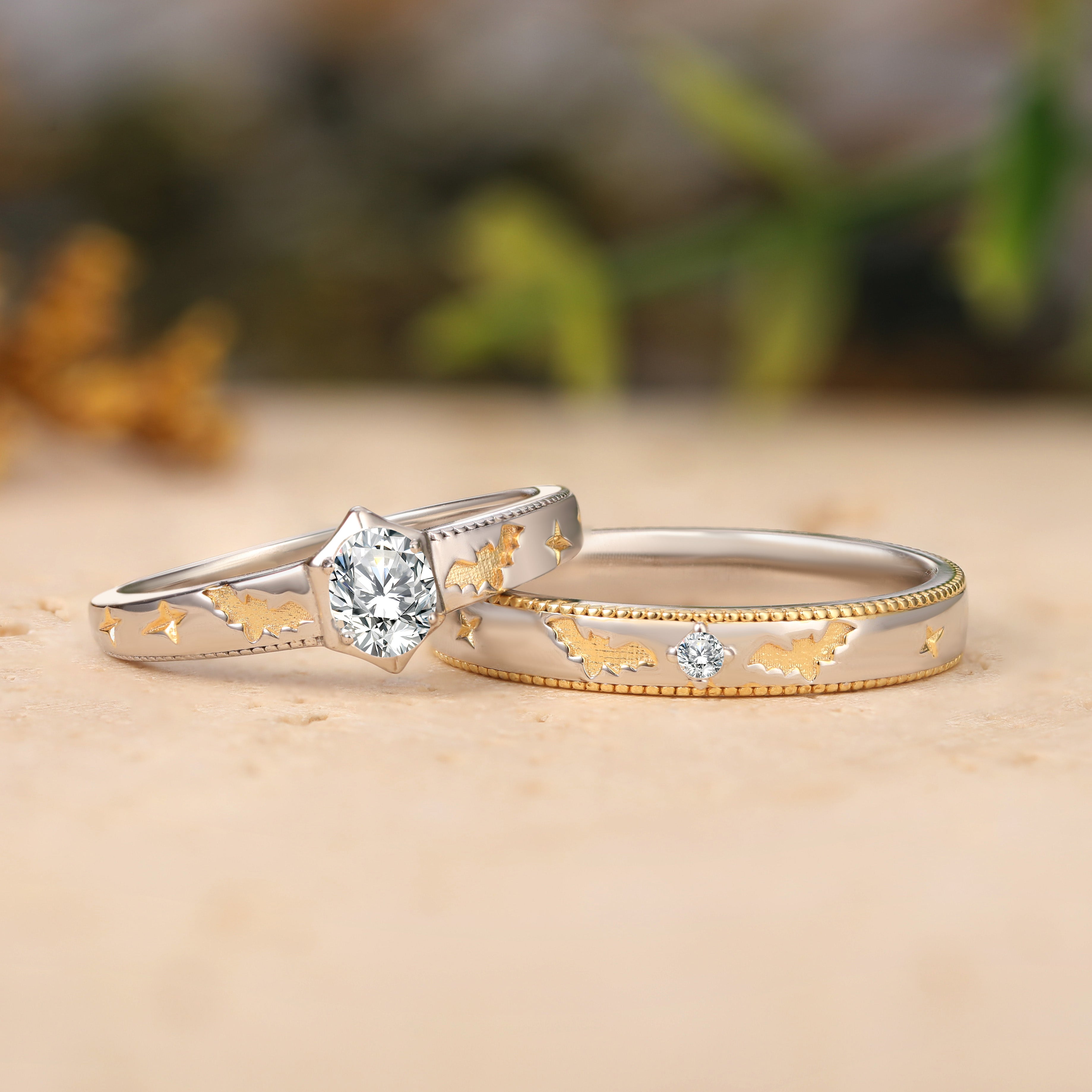 Two gold and silver rings with diamond accents on a wooden surface.