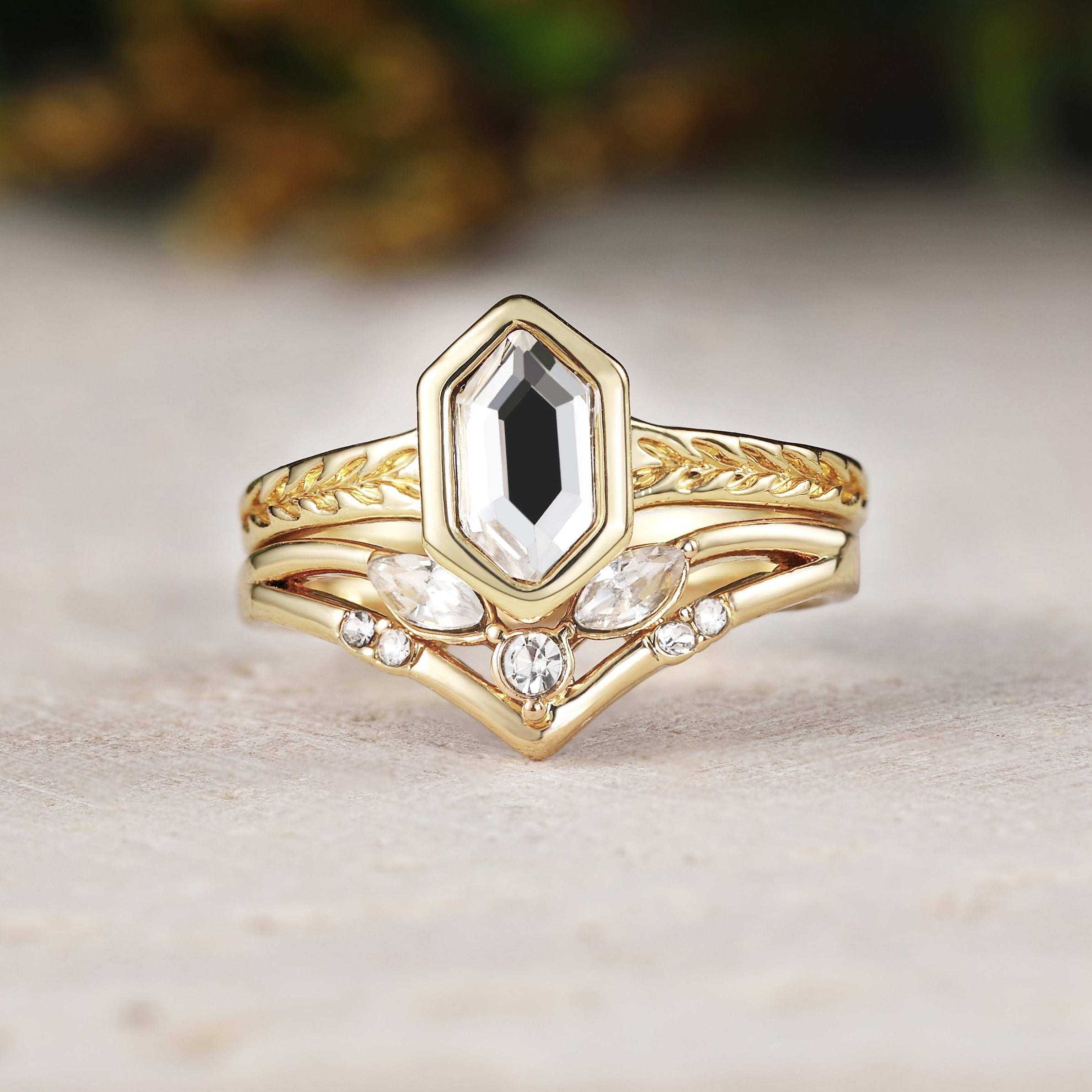 Gold ring with a central black gemstone and diamond accents on a light surface.
