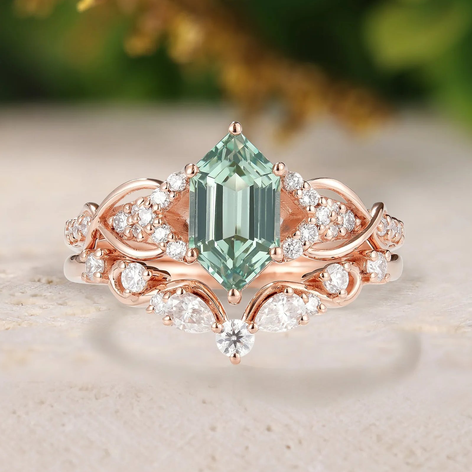 Rose gold ring with a green gemstone and diamond accents on a light background
