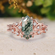 Rose gold ring with green gemstone and diamond accents on a neutral background