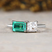 Ring with green gemstone and clear stone on a neutral background