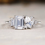 Diamond ring with emerald-cut center stone and baguette side stones on a neutral background