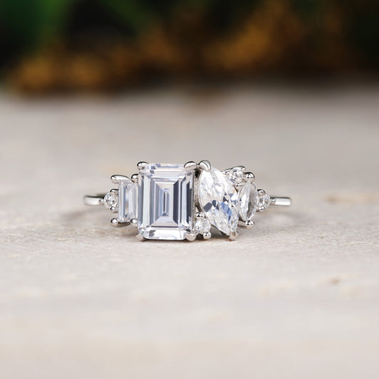 Diamond ring with emerald-cut center stone and baguette side stones on a neutral background