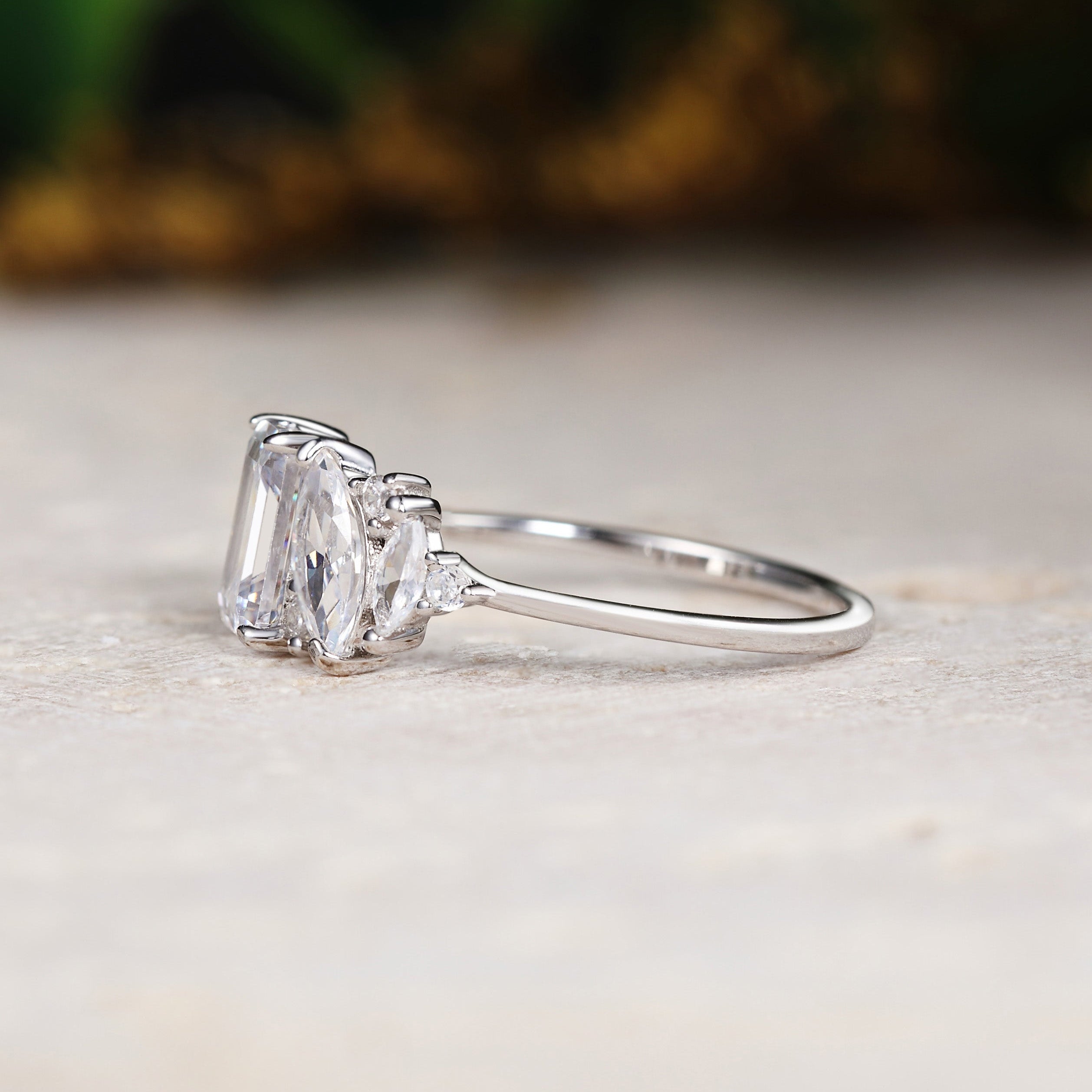 White gold ring with a large diamond and smaller stones on a light surface.
