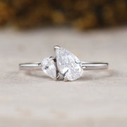 Silver ring with two pear-shaped diamonds on a wooden surface