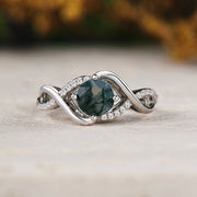 Silver ring with a green gemstone on a wooden surface