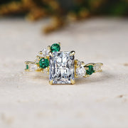 Gold ring with emerald and diamond accents on a light surface
