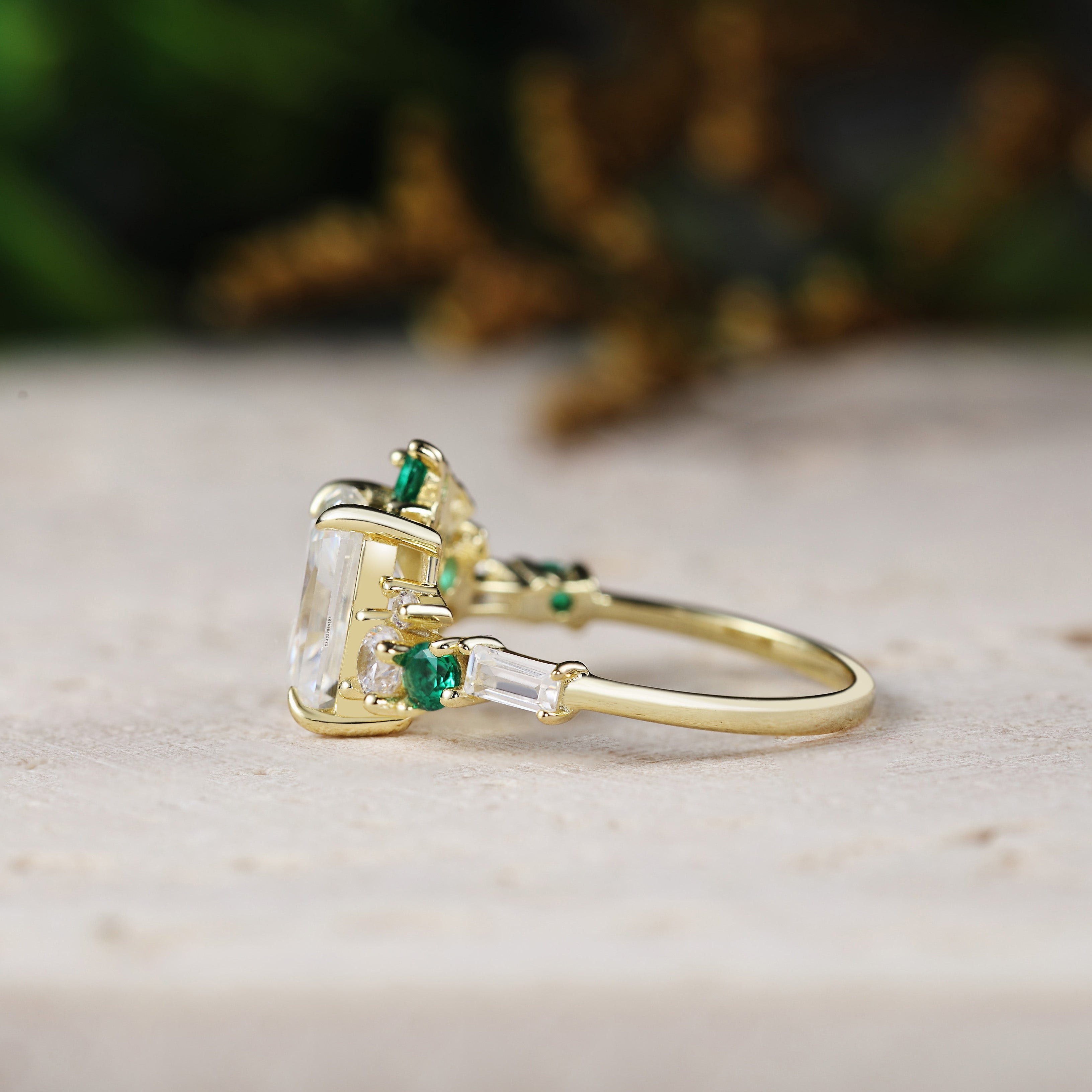 Gold ring with emerald and diamond stones on a neutral background