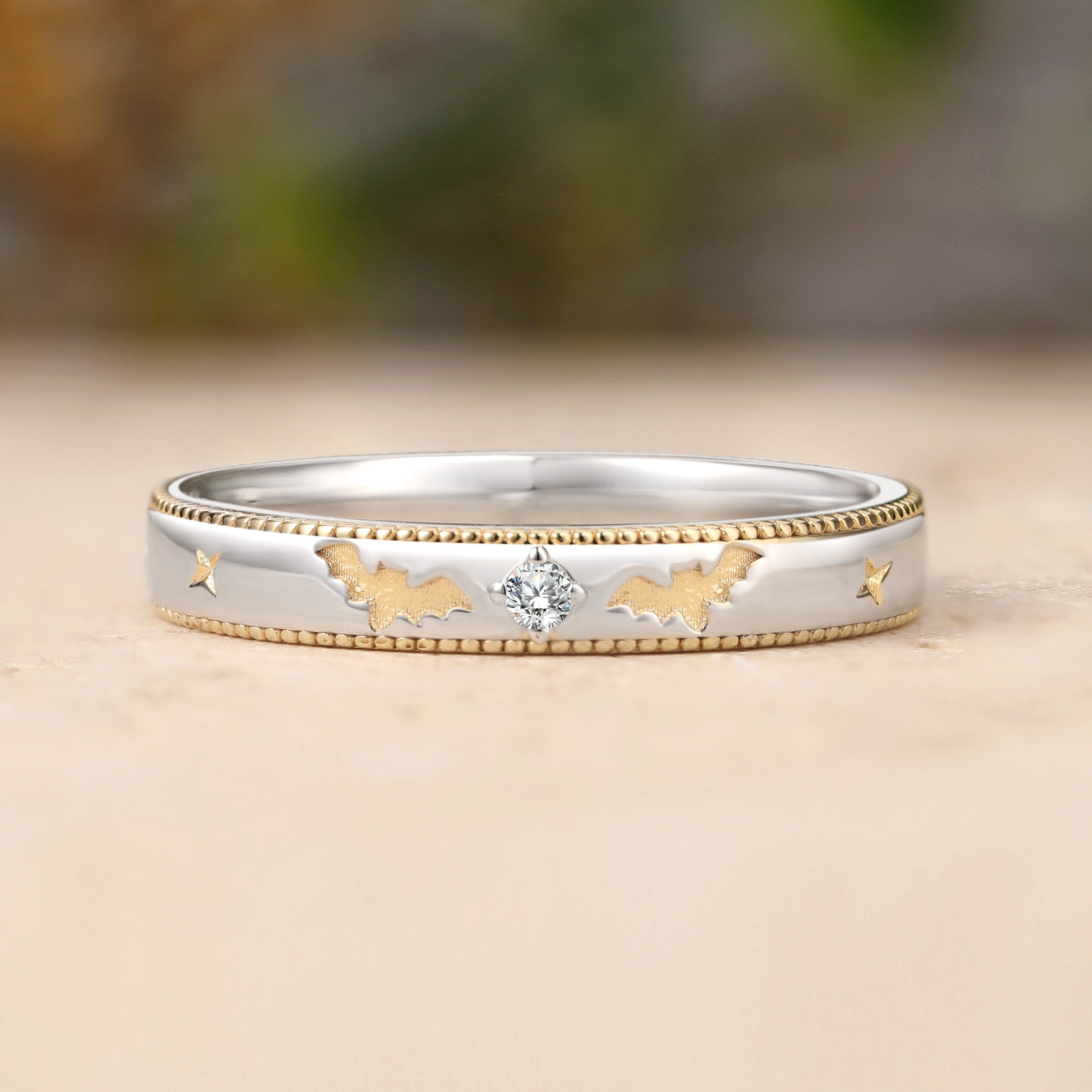 Silver ring with gold accents and a central diamond on a wooden surface