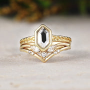 Gold ring with a central black gemstone and diamond accents on a light surface.