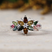 Multicolored gemstone ring on a wooden surface with a blurred natural background