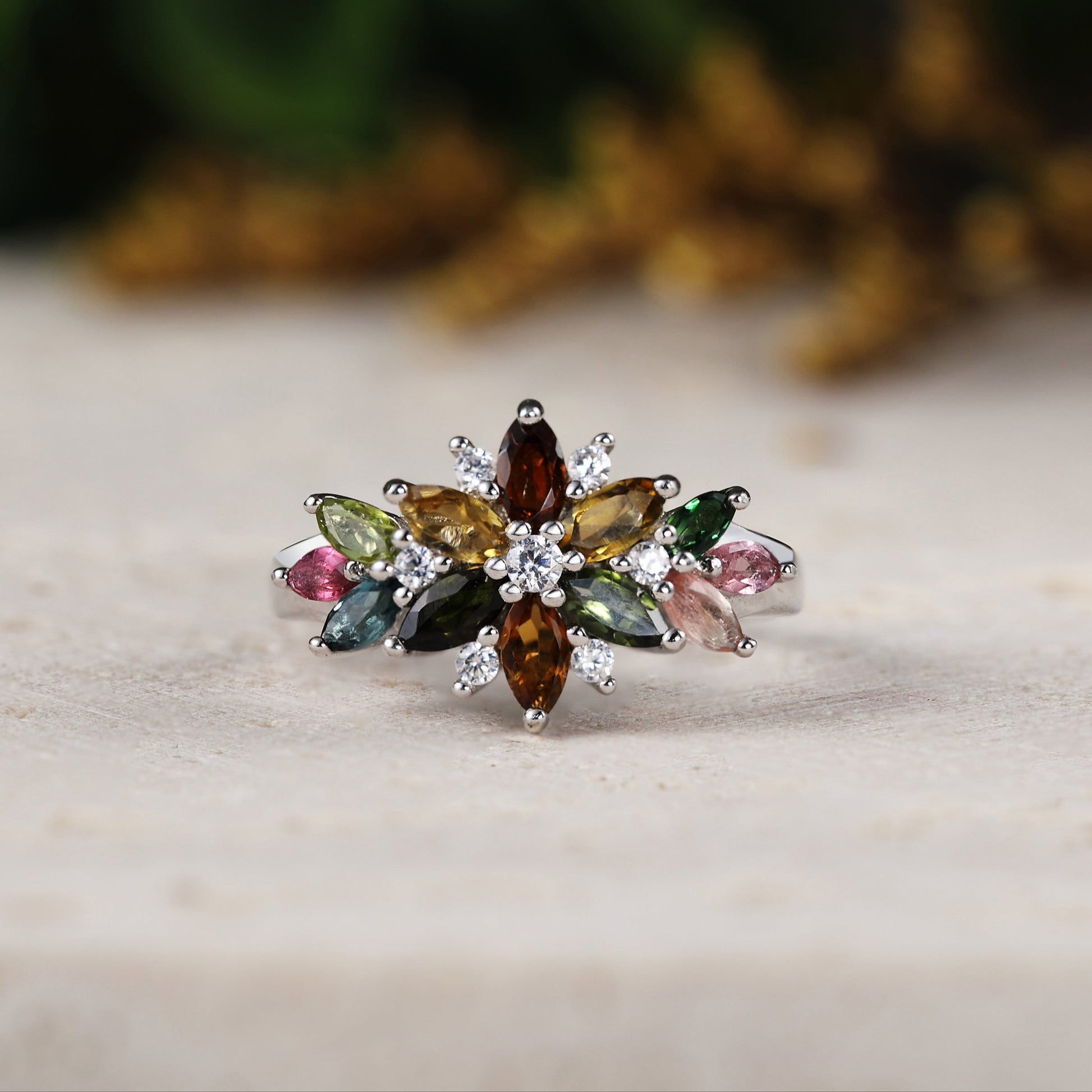 Multicolored gemstone ring on a wooden surface with a blurred natural background