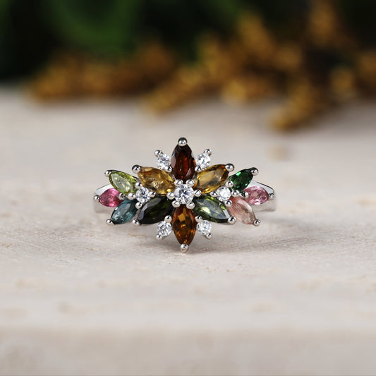 Multicolored gemstone ring on a wooden surface with a blurred natural background