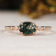 Rose gold ring with a green gemstone on a light background