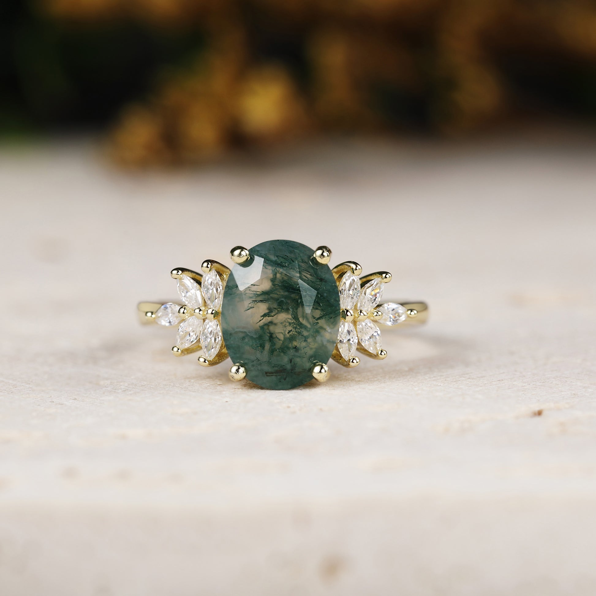 Yellow gold ring with a green gemstone and diamond accents on a light background