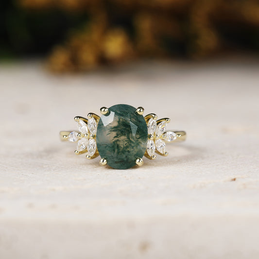 Yellow gold ring with a green gemstone and diamond accents on a light background