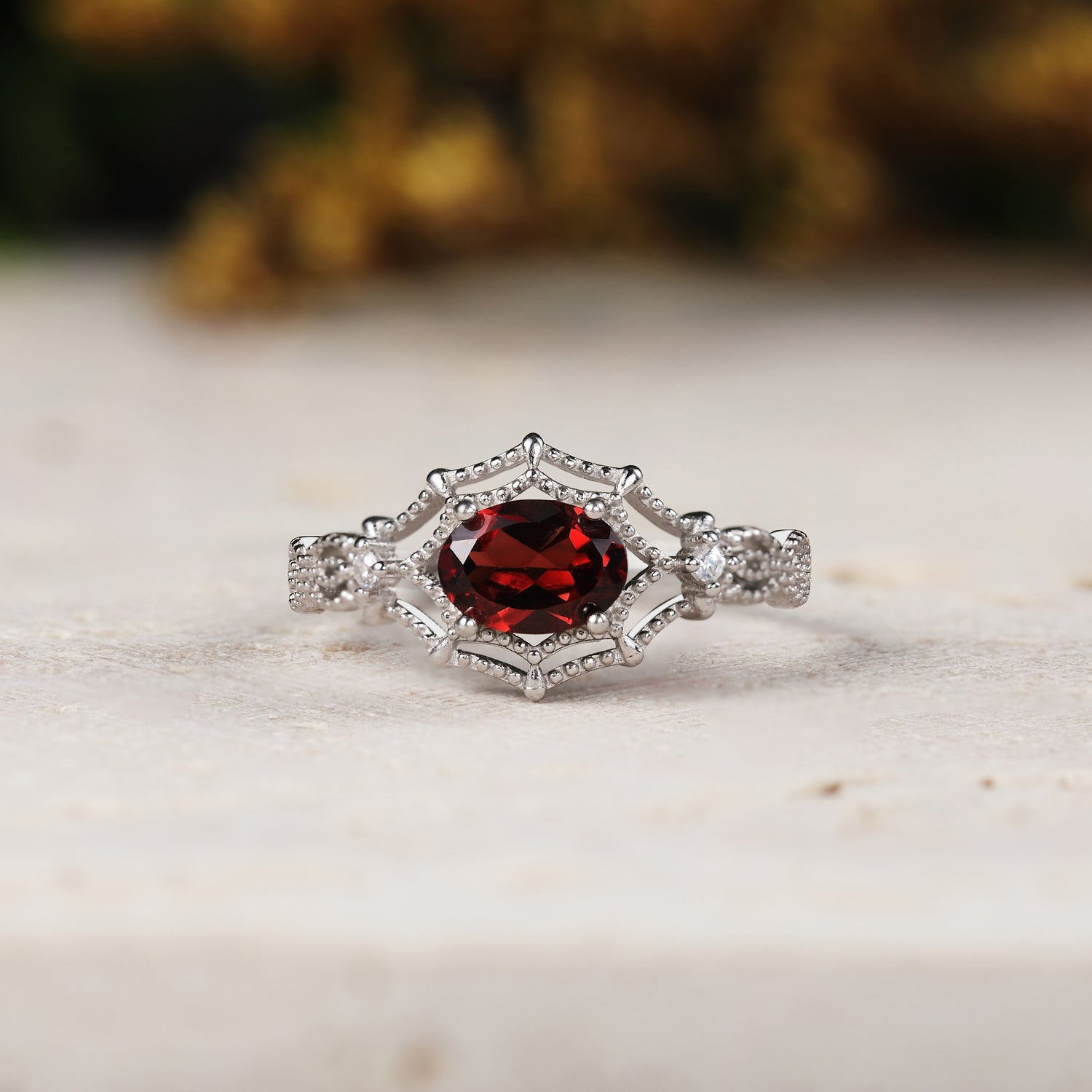 White gold ring with a red gemstone on a light background