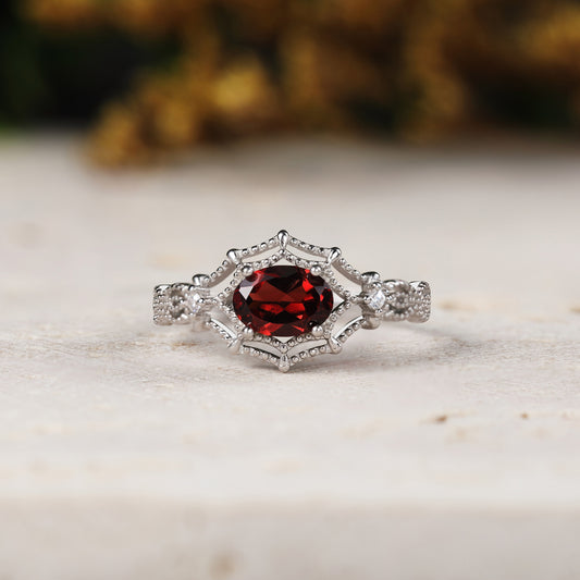 White gold ring with a red gemstone on a light background