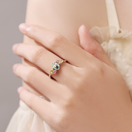 Close-up of a hand wearing a ring with multicolored gemstones on a neutral background