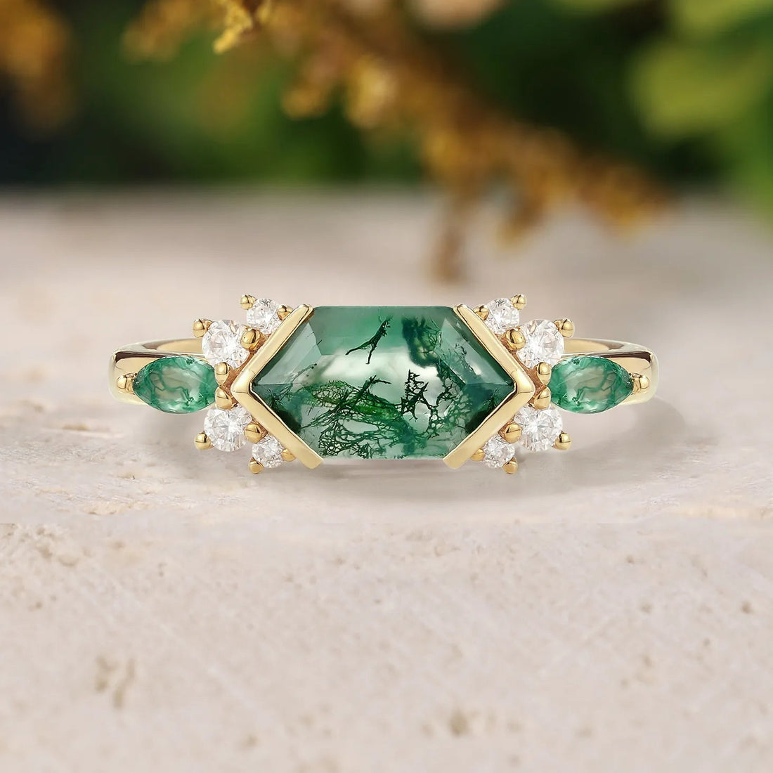 Gold ring with green gemstones on a light surface