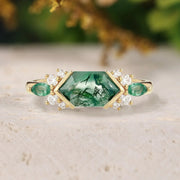 Gold ring with green gemstones on a light surface