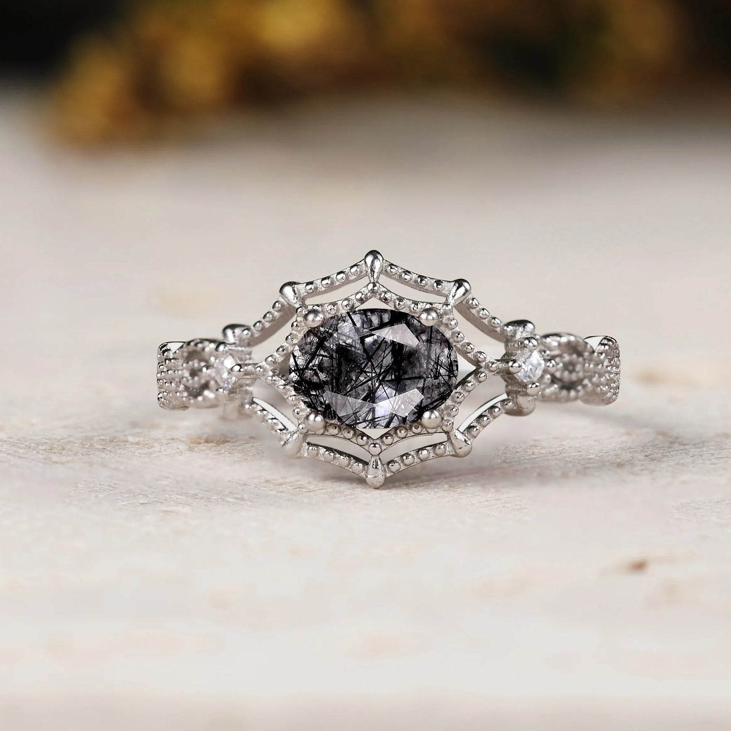 Silver ring with a central black diamond on a marble surface