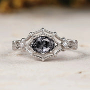 Silver ring with a central black diamond on a marble surface