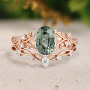 Rose gold ring with a green gemstone and small diamonds on a beige surface.
