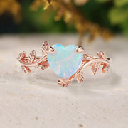 Heart-shaped opal ring with rose gold vine design on a natural background