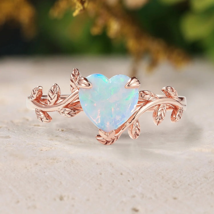 Heart-shaped opal ring with rose gold vine design on a natural background