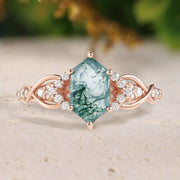 Rose gold ring with a green gemstone on a neutral background
