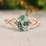 Rose gold ring with a green gemstone and diamond accents on a neutral background