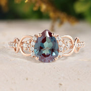 Rose gold ring with a large gemstone and smaller diamonds on a beige surface.