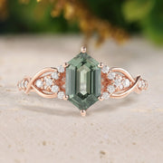 Rose gold ring with a green gemstone and diamond accents on a neutral background